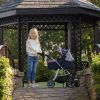 image of a girl stoof under a pergola holding the handles of a dolls pram
