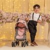 image of a small boy with a pink dolls pushchair