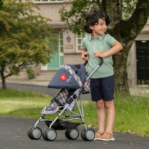 a boy in a green shirt pushing a dolls pushchair that has a checked pattern