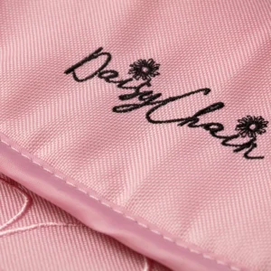 Daisy Chain Connect Dolls Pram in Classic Pink fabric. Close up of the apron with an embroidered Daisy Chain logo in black.