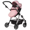 Daisy Chain Connect Dolls Pram in Classic Pink fabric. Shown in pushchair mode with a pink apron on the shown on a side angle with the handle to the left side. Hood is up and is pink with accents of Silver metal with a black and pink flower rosette and an with an embroidered Daisy Chain logo in silver. Wheels are black and Silver with a shopping basket at bottom of pushchair which is black. The frame of the pushchair is silver.
