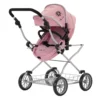 Daisy Chain Destiny Travel System Pram in Classic Pink fabric. Shown in pushchair mode. Photo shows the pushchair on a front facing angle with the handle at the front of the photo. Hood is up and is pink with accents of Silver metal with a black and pink flower rosette and an with an embroidered Daisy Chain logo in silver. Wheels are black and Silver with a shopping basket at bottom of pushchair which is Silver, like the frame. The frame of the pushchair is silver.