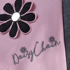 Daisy Chain Little Zipp Dolls Pushchair in Classic Pink fabric. Close up of hood with a black and pink flower rosette.