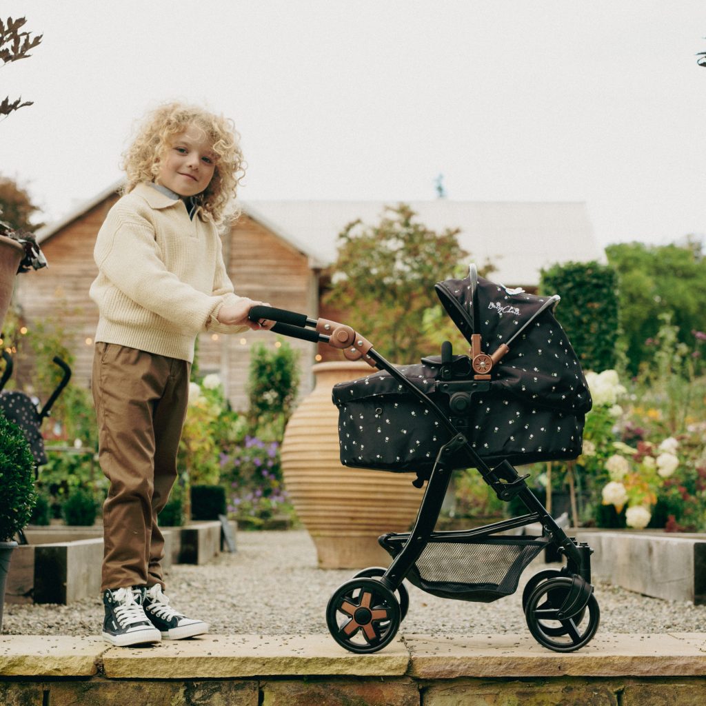 image of boy in brown coat with the daisy chain connect 5 in 1 dolls pram in limited edition twighlight pattern