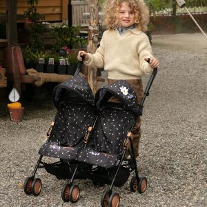 a young boy with blonde curly hair pushing a double dolls pushchair