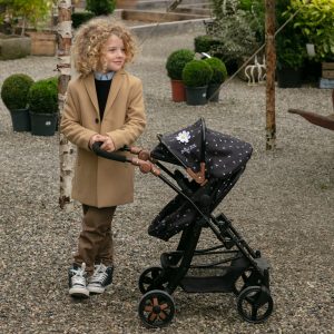 image of boy in brown coat with the daisy chain connect 5 in 1 dolls pram in limited edition twighlight pattern