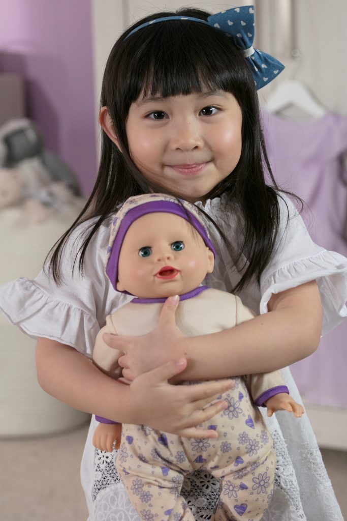image of a young girl holding a doll that has a pink and purple outfit on