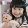 image of a girl with a headband smiling and holding a doll