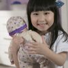image of a girl holding a doll close to her shoulder