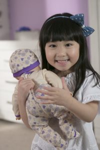 image of a girl holding a doll close to her shoulder