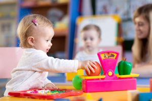 image of a toddler playing pretend shop with pink plastic weighing scales