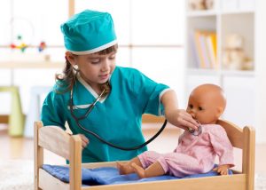image of a girl pretending to be a doctor with her baby doll
