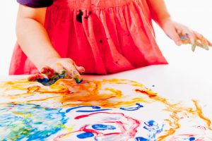 image shows a young child making a messy finger painting