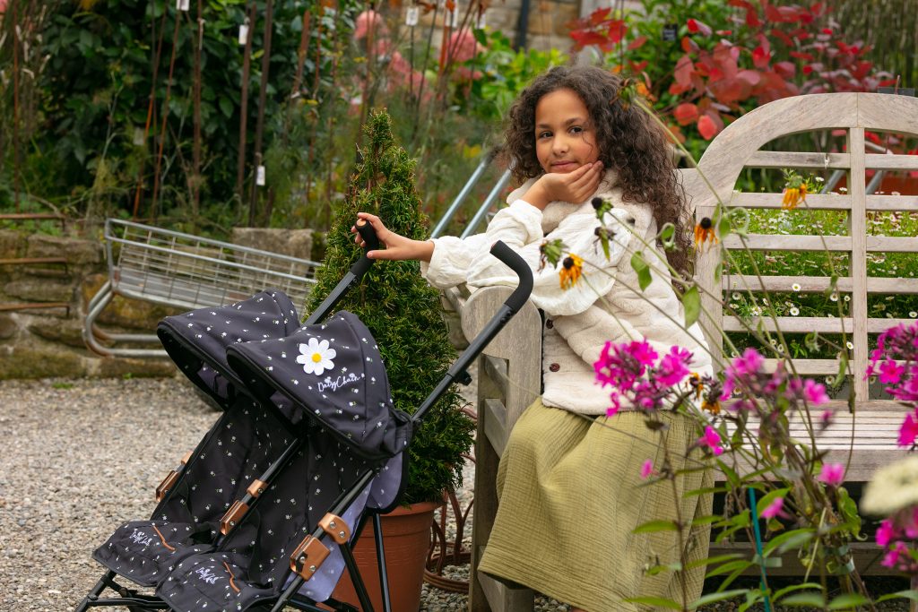image shows a young girl with her twighlight dolls pushchair