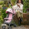 image shows a young girl in a white coat holding her daisy chain zipp zenith dolls pushchair in classic pink