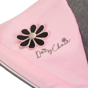 Daisy Chain Zipp Zenith Dolls Pushchair in Classic Pink fabric. Close up of hood showing the daisy rosette which has black petals and a silver centre. Underneath this is an embroidered Daisy Chain logo in silver. To the right is a strip of the grey fabric.