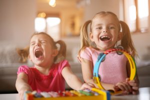 image shows two young girls laughing with music instruments