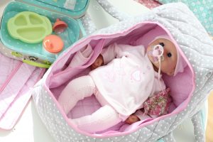 image shows a baby doll in a carry coy