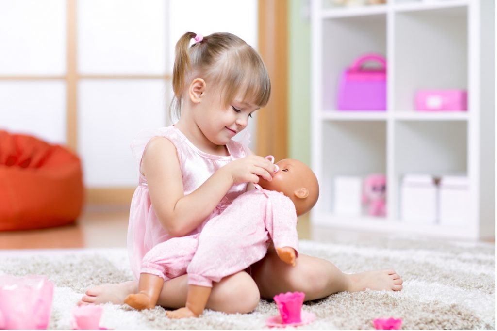 image shows a blonde girl playing with a baby doll