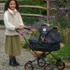 image of a young girl with a dolls pushchair that is black with a small daisy pattern all over it
