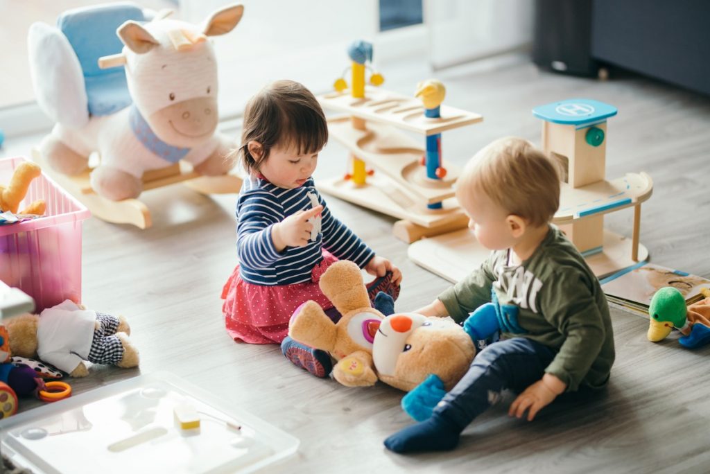 image of two children playign with a teddy bear