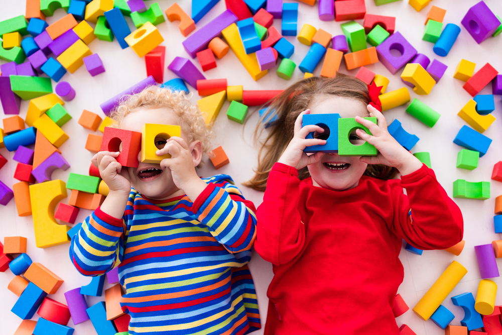 image of two young children surrounded by bright coloured building blocks