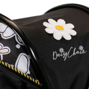 Detail of Daisy Chain Connect Dolls Pram hood showing the flower rosette in white with yellow centre and Daisy Chain logo embroidered underneath.