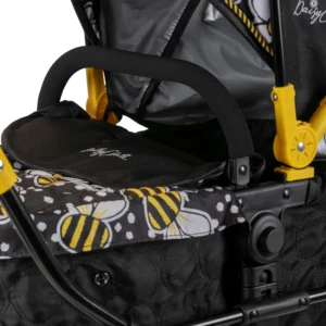 Daisy Chain Destiny Travel System Dolls Pram in Bumblebee fabric. Close up of cot with a black quilted fabric body, an apron on top in bumblebee fabric and bumper bar in black EVA foam.