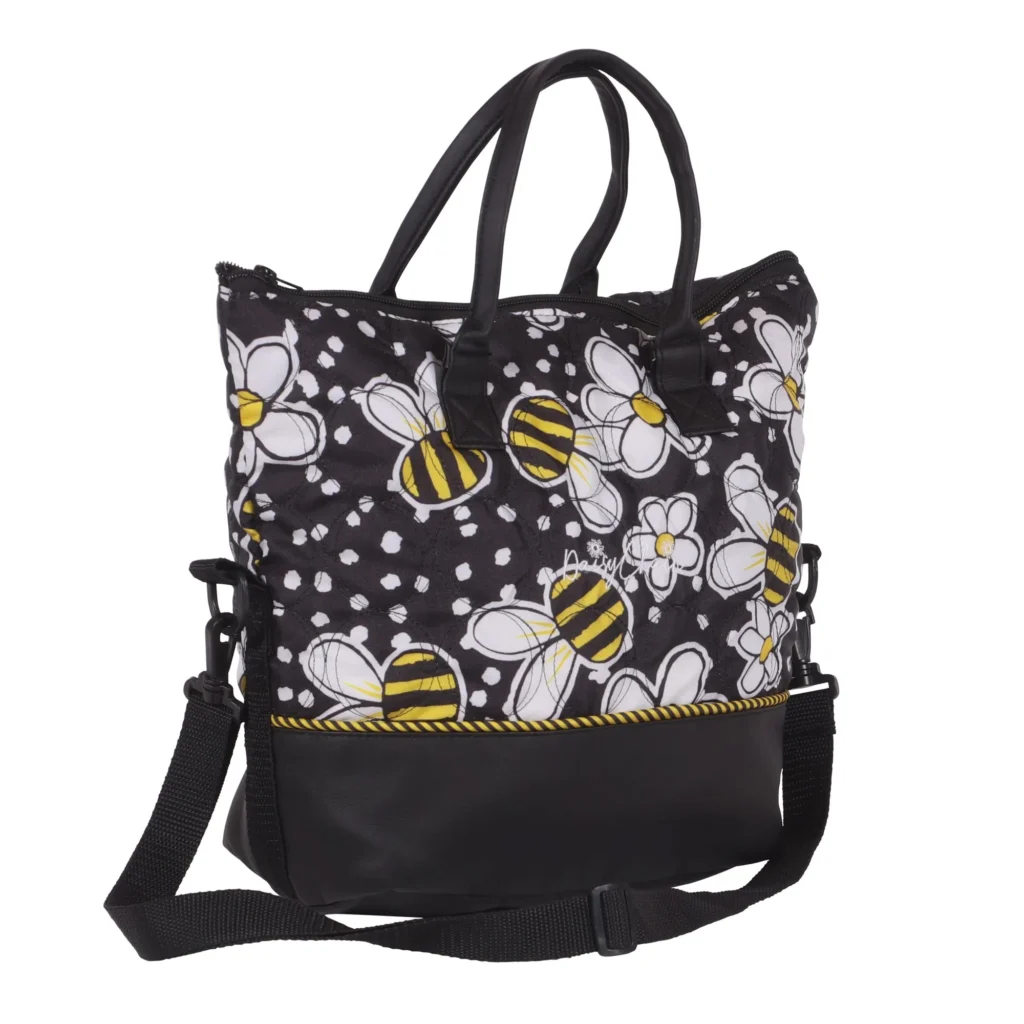 Daisy Chain Luxury Tote Bag in Bumblebee fabric . Bag has carry handles and shoulder strap is on ground in front of bag. Bag is in bumblebee fabric with a black leatherette band around the bottom of the bag.
