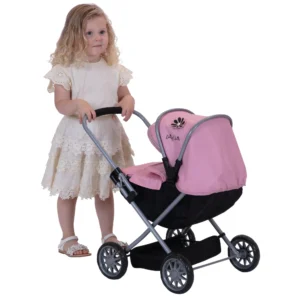 Daisy Chain Pocket Pram in Classic Pink - For ages 18 months - 3 years. Silver frame, black cot and pink hood. Girl standing next to the pram in a summer dress.