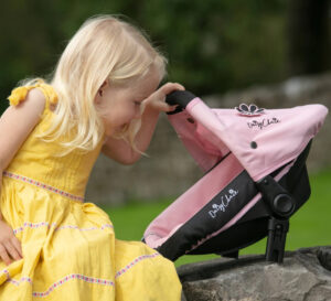 Image of a toddler playing with a dolls pram accessories.